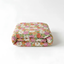 A floral print bedspread or duvet cover is folded and placed on a white surface.