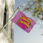 The “I Am Literally Just A Festival Girl Flag” features colorful text that says “I am literally just a festival girl,” along with vibrant illustrations of a rainbow, mushrooms, stars, and waves. Displayed on a flagpole outside beside a building with blurred trees in the background, this lively flag makes the perfect go-to accessory for music festivals or as a standout festival totem.