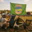 A person kneels by a tent, setting up the Festival Flag—a vibrant Boho Camp Flag that reads EPIC PLAYLIST SOCIETY—in colorful letters at a sunny outdoor campsite decorated with Music Festival Campsite Decor and other tents in the background.
