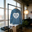 A blue hoodie with the text "DISCO TRIBE CO" printed on it, hanging on a clothing rack in a room with a record player and a potted plant.
